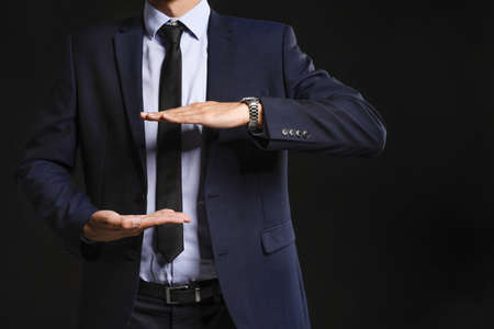 Young businessman holding something on dark backgroundの写真素材