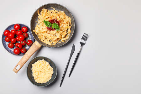 Frying pan with tasty pasta, tomato sauce and cheese on white backgroundの写真素材