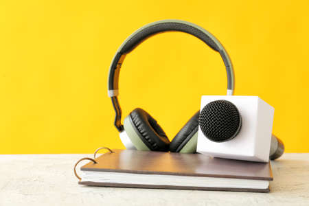 Microphone, headphones and notebook on table against color backgroundの写真素材
