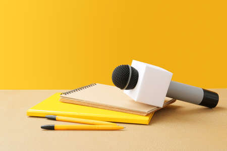 Microphone and notebooks on table against color backgroundの写真素材