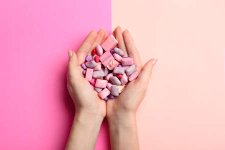 Female hands with chewing gums on color background