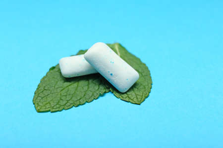 Chewing gums and mint on color backgroundの写真素材
