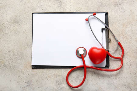 Clipboard, heart and stethoscope on light tableの写真素材