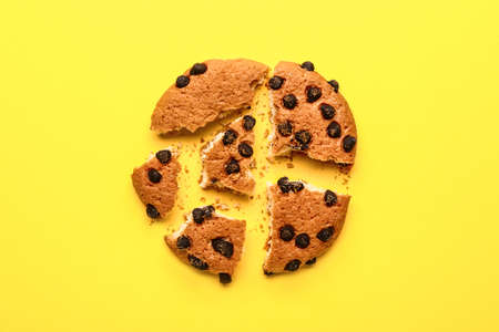 Tasty crushed cookie with chocolate chips on color background