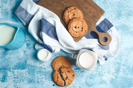 Tasty cookies with chocolate chips and milk on table
