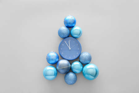 Alarm clock with Christmas balls on white background