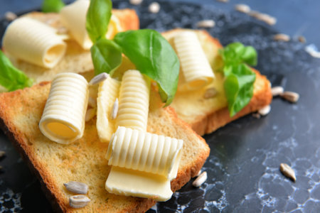 Fresh bread with butter and basil on board, closeup