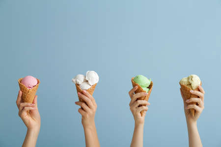 Female hands with sweet ice-cream on color backgroundの写真素材