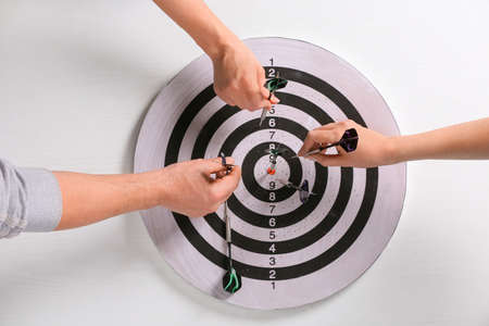 People taking darts out of dartboardの写真素材