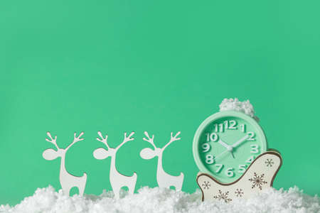 Clock, deer with sledges and snow on color background. Christmas countdown concept
