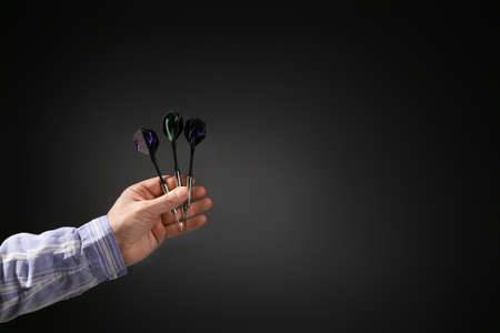 Male hand with darts on dark background