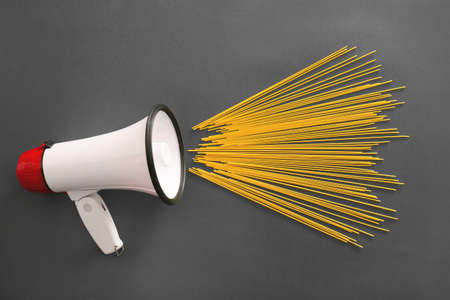 Megaphone with raw pasta on dark background