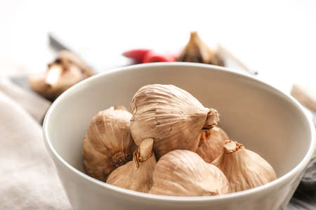 Bowl with black garlic on table, closeupの写真素材