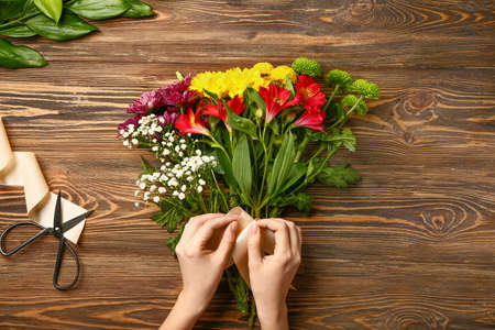 Female florist making beautiful bouquet at tableの写真素材