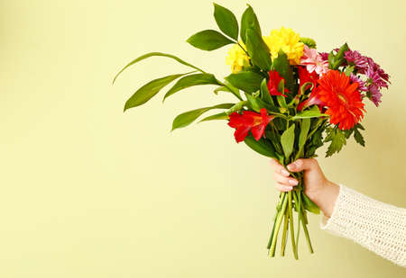 Hand of florist with beautiful bouquet on color background