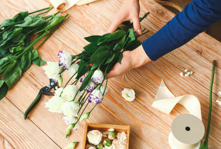 Female florist making beautiful bouquet at table