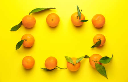 Frame made of sweet tangerines on color background