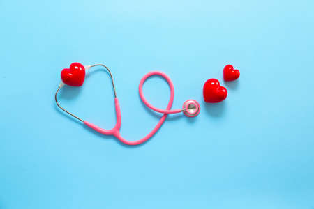 Stethoscope and red hearts on color background. Cardiology concept