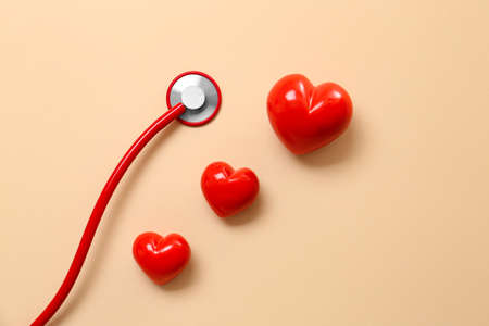 Stethoscope and red hearts on color background. Cardiology concept