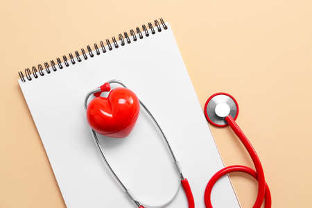 Stethoscope, notebook and red heart on color background. Cardiology conceptの写真素材