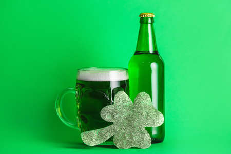 Green beer and clover on color background. St. Patrick's day celebrationの写真素材