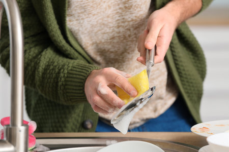 Young man washing dishes in kitchen, closeupの写真素材