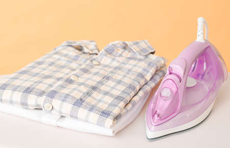 Iron and clean clothes on board against color backgroundの写真素材