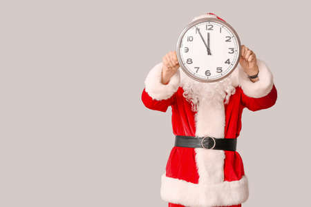 Santa Claus with clock on light background. Christmas countdown concept