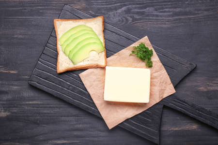 Fresh butter with bread and avocado on dark tableの写真素材