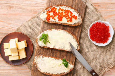 Slices of bread with tasty butter and caviar on wooden tableの写真素材
