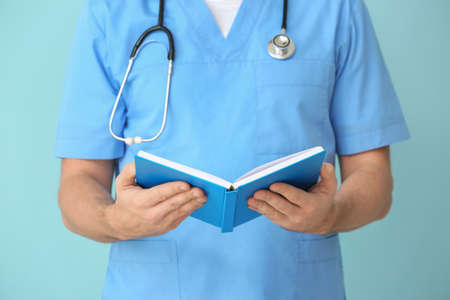 Male cardiologist with book on color backgroundの写真素材