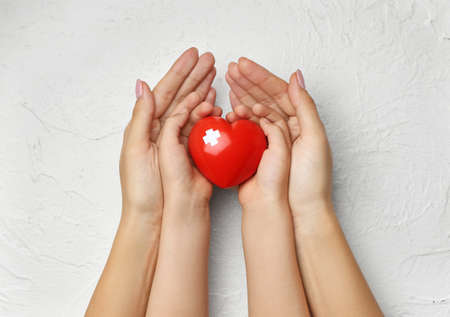 Hands of child and adult with red heart on white background. Cardiology conceptの写真素材