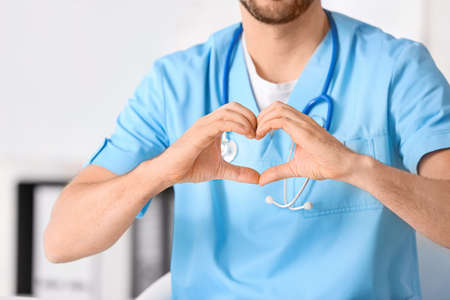 Male cardiologist making heart with his hands in clinicの写真素材