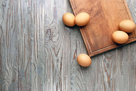 Board with fresh eggs on wooden backgroundの写真素材