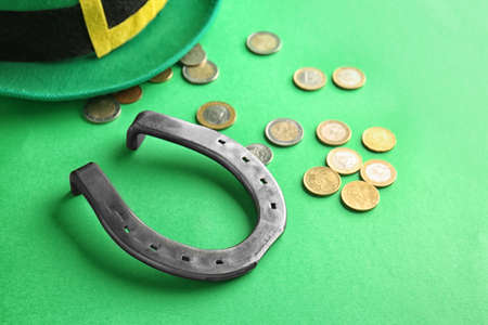 Hat of leprechaun with horseshoe and coins on color background. St. Patrick's day celebrationの写真素材