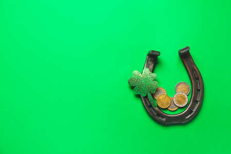 Horseshoe with coins and clover on color background. St. Patrick's day celebration