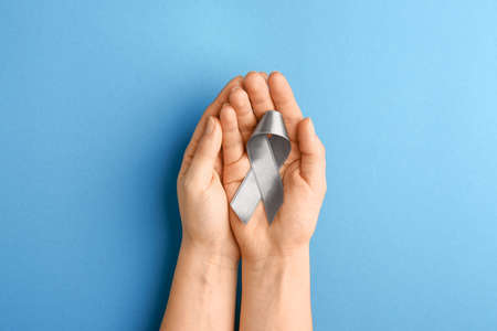 Female hands with silver ribbon on color backgroundの写真素材