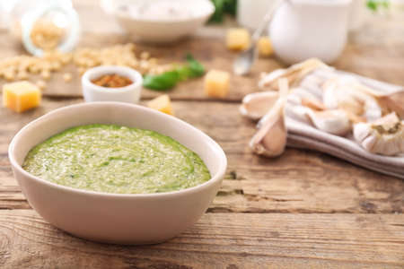Bowl of tasty pesto sauce on wooden tableの写真素材
