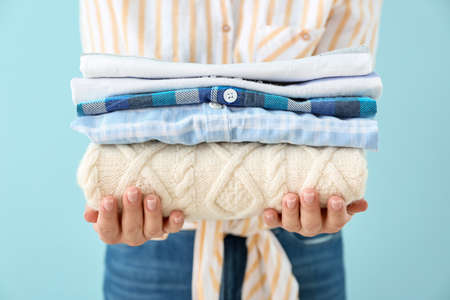 Young woman with clean laundry on color background, closeup