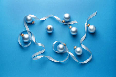 Beautiful Christmas balls with ribbon on color backgroundの写真素材