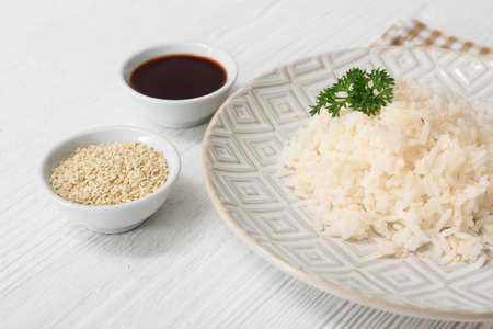 Plate with boiled rice and soy sauce on white tableの写真素材