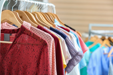 Stylish clothes on hangers in modern store, closeup
