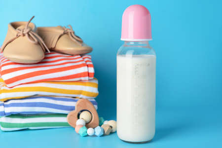 Bottle of milk for baby with clothes on color backgroundの写真素材