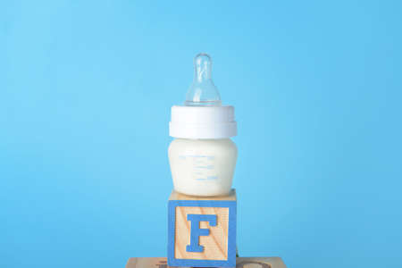 Bottle of milk for baby with cube on color backgroundの写真素材