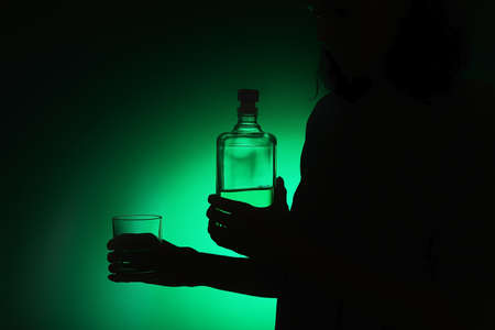 Silhouette of woman with alcohol on color backgroundの写真素材