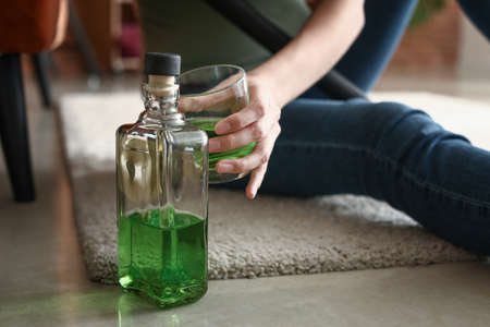 Woman drinking absinth at home. Concept of alcoholismの写真素材