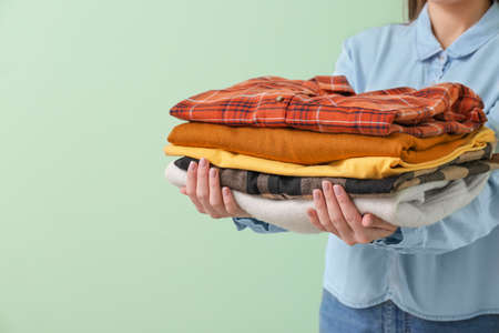 Young woman with clean clothes on color background, closeup