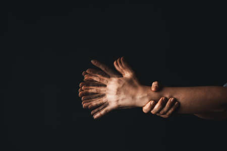 Hands of woman suffering from Parkinson syndrome on dark backgroundの写真素材