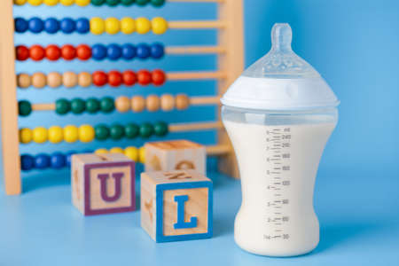 Bottle of milk for baby with toys on color backgroundの写真素材