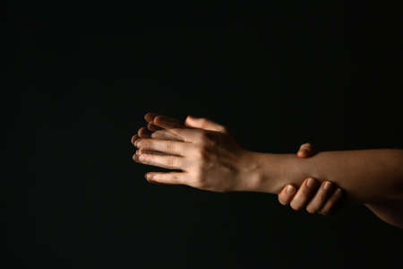 Hands of woman suffering from Parkinson syndrome on dark backgroundの写真素材